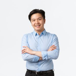 Business, finance and people concept. Professional confident asian businessman with teeth braces, smiling pleased, cross arms chest, standing white background, Salesman showing product.
